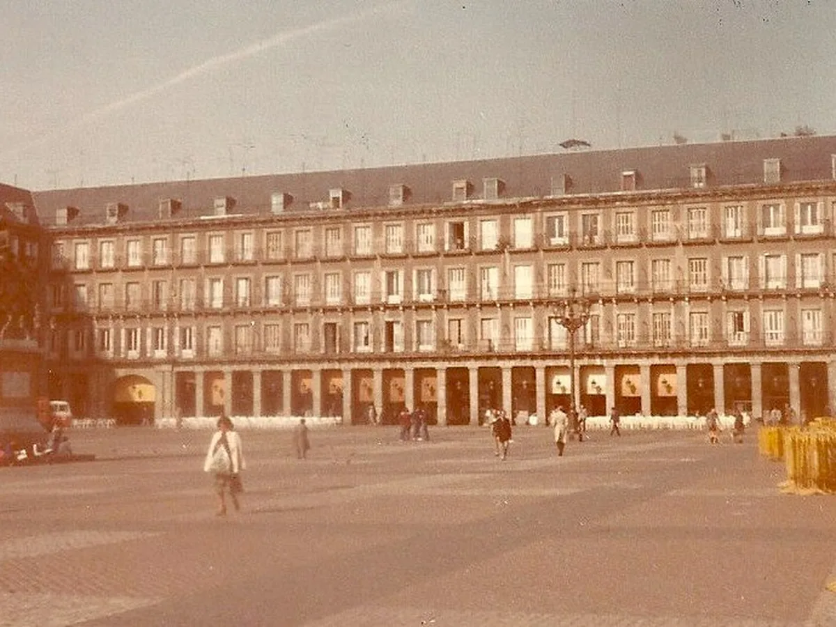 A vintage photograph of Plaza Mayor in Madrid, its arcaded facade and an equestrian statue in the square